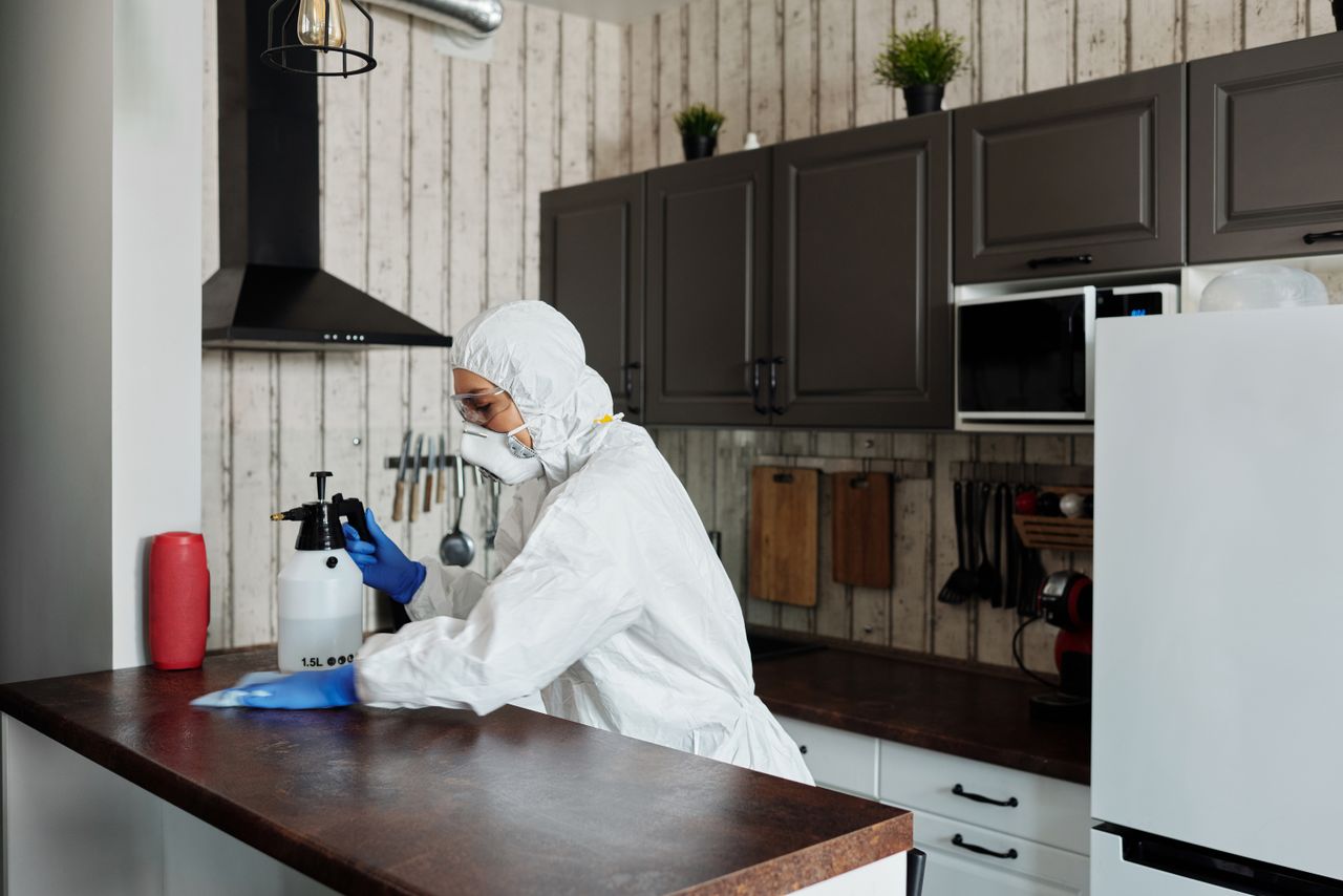 Un intervenant équipé de protections désinfecte une cuisine afin de garantir un environnement propre et sûr.